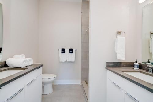 a white bathroom with two sinks and a toilet at Mason Lofts at West End in Nashville