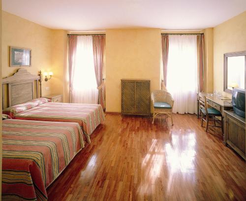 a hotel room with two beds and a desk at Balneario de Alhama de Granada in Alhama de Granada