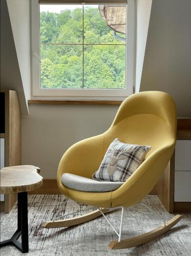 a yellow chair in a living room with a window at Willa Spa Scaliano in Kudowa-Zdrój