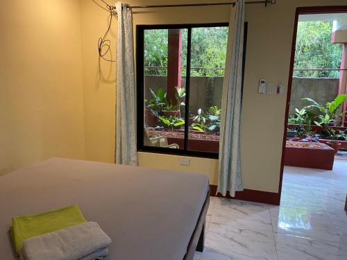 a bedroom with a bed and a large window at One 4 Da Road in Panglao