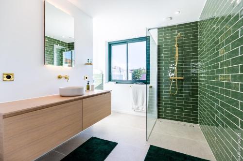 La salle de bains est pourvue d'un lavabo et d'une douche avec du carrelage vert. dans l'établissement VILLA BIBI CHERI Elégante Suite de 35 M2, à Biarritz