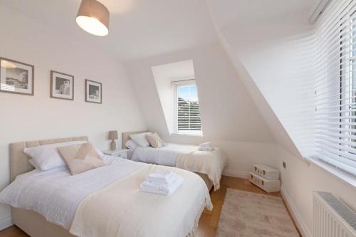 two beds in a white room with two windows at Spacious Two Bed loft Apartment in Birchanger