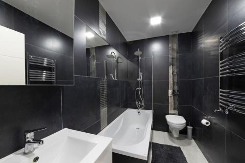 a bathroom with a tub and a toilet and a sink at Spacious Two Bed loft Apartment in Birchanger