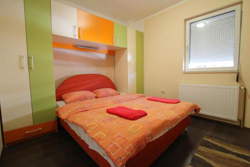 1 dormitorio con 1 cama con 2 almohadas rojas en Apartmani Kovacevic, en Zlatibor
