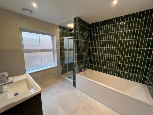 y baño con bañera, lavamanos y bañera. en Luxury Cromer cottage with hot tub & log burner in Town, en Cromer