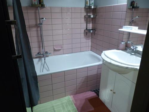 a pink tiled bathroom with a tub and a sink at Zeezicht Studio Alisa in Blankenberge