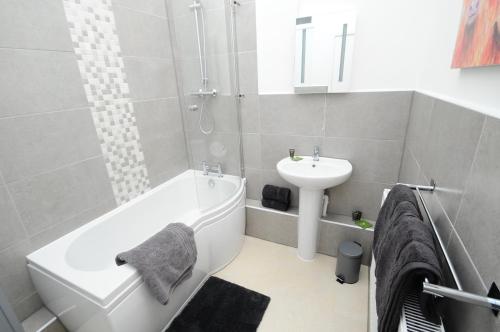 uma casa de banho com uma banheira branca e um lavatório. em Newly refurbished next to University Hospital Coventry em Walsgrave on Sowe
