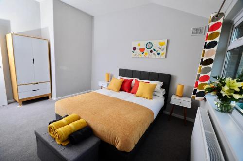 a bedroom with a large bed with yellow and red pillows at Newly refurbished next to University Hospital Coventry in Walsgrave on Sowe