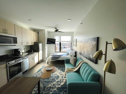a living room with a blue couch and a kitchen at Sleepover Studio Apartments Des Moines in Des Moines