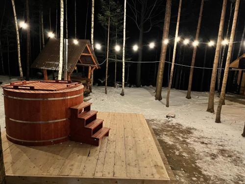 a wooden platform with a wooden barrel and a house at Pensiunea Ionela in Zemeş