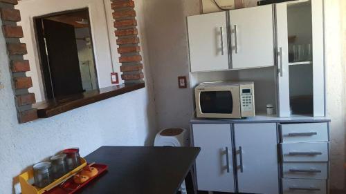 una pequeña cocina con mesa y microondas en Casefo, en Aguas Dulces