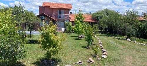 a house with a yard with trees and rocks at Ayres Serranos in Merlo