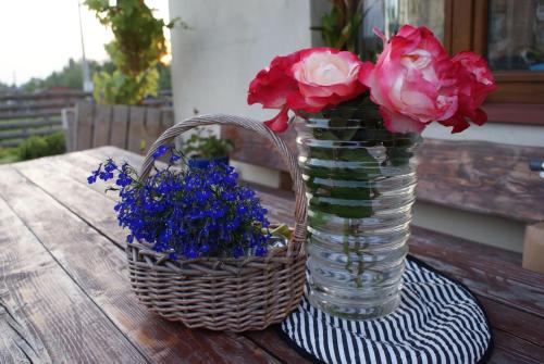a vase with flowers and a basket on a table at Agroturystyka u Aleksa in Krajno-Zagórze