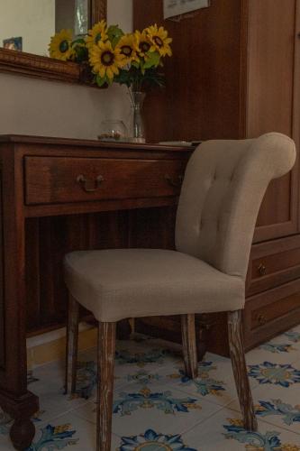 a chair in front of a desk with a vase of flowers at La Casa del Limoneto in Favignana