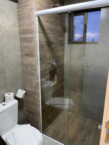 a bathroom with a toilet and a glass shower at Ilusion flat Ponta Negra in Natal