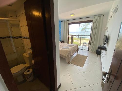 a room with a bed and a bathroom with a window at Pontal Hostel - Pousada Pontal RJ in Rio de Janeiro
