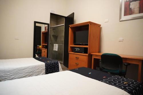 a bedroom with two beds and a desk and a chair at Hotel Boutique de Firma in Monterrey