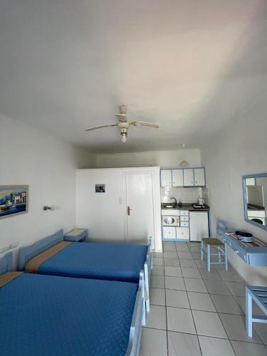 a bedroom with a blue bed and a kitchen at Argo Studios in Myrties