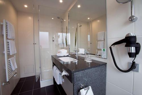 a bathroom with a sink and a shower at Nordsee Hotel City in Bremerhaven