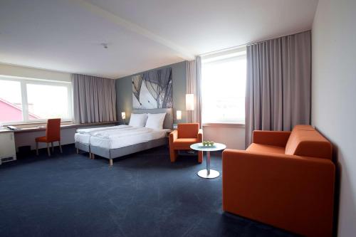 Nordsee Hotel City في برمرهافن: غرفة فندقية بسرير وطاولة وكراسي