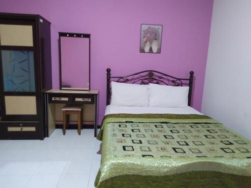 Dormitorio púrpura con cama y espejo en CAMELIA HOLIDAY APARTMENT en Kuah