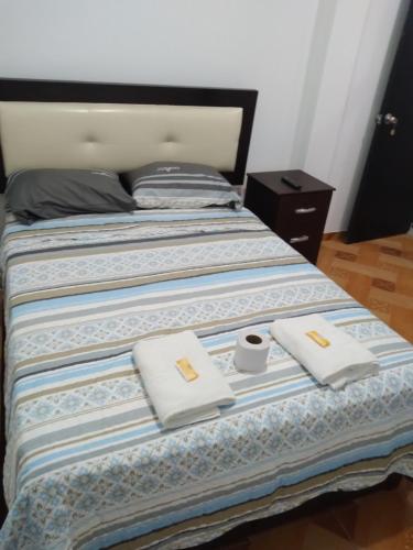 a bed with two white towels and a cup on it at La Petite Maison in Nazca