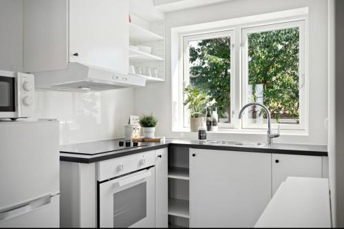 een witte keuken met een wastafel en een raam bij A Place To Stay Stavanger, apartment 2 in Stavanger