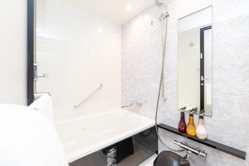 a white bathroom with a sink and a shower at Hiyori Hotel Osaka Namba Station in Osaka