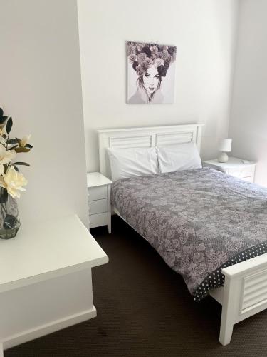 a white bedroom with a bed and a vase of flowers at Bundalong Villas in Bundalong
