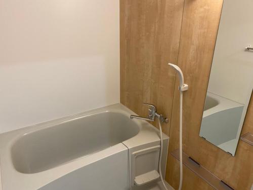 a bath tub in a bathroom with a mirror at ホテルトーマス前島 in Naha
