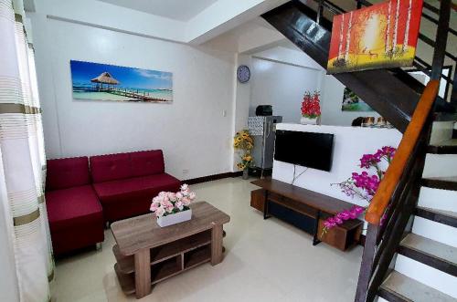 a living room with a red couch and a television at Kaitleen Home Stay Door 3 in Tacloban