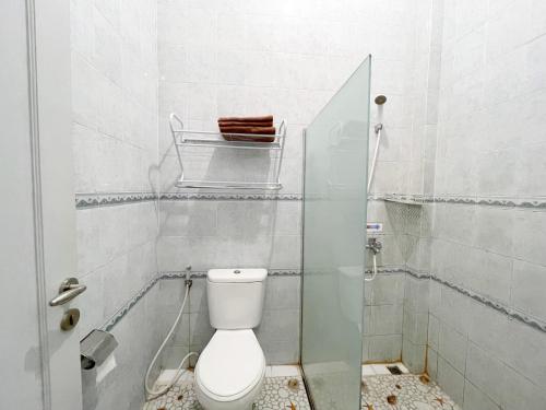 a bathroom with a toilet and a glass shower door at Ministry Homestay in Yogyakarta