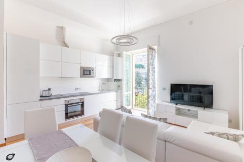 a white kitchen with a dining room table and chairs at Elena House Apartments in Viareggio