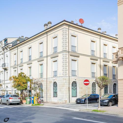 a large white building with cars parked in front of it at Elena House Apartments in Viareggio