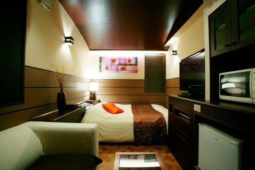 a hotel room with a bed and a tv at HOTEL CHECK INN BALI adult only in Tokyo