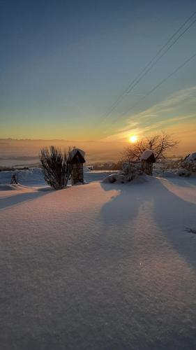 a snow covered field with a sunset in the background at Apartament Huba in Huba