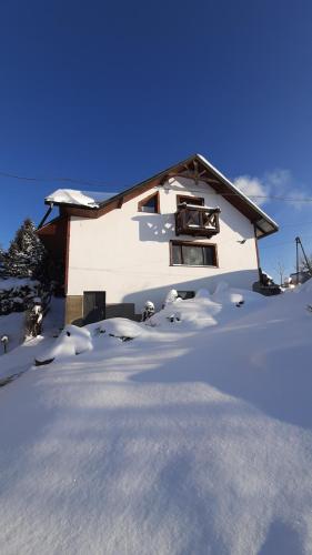 a house with snow on the ground in front of it at Apartament Huba in Huba