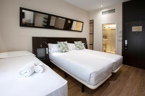 a hotel room with two beds and a television at Petit Palace Ruzafa in Valencia