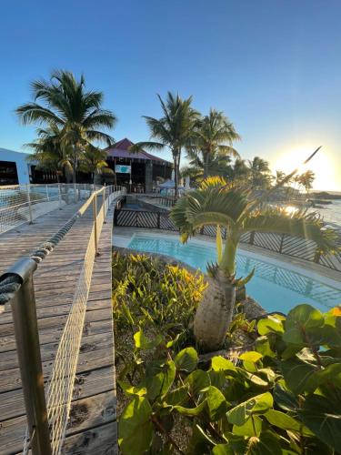 a resort with a pool and palm trees and a boardwalk at Studio 25 m Manganao Joela 4 personnes avec machine a laver in Saint-François
