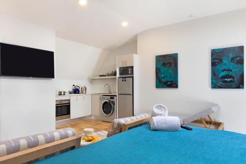 a bedroom with a blue bed and a kitchen at Urban Oasis Aparthotel in Cape Town