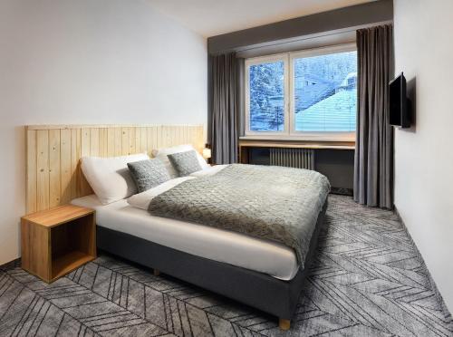 - une chambre avec un grand lit et une fenêtre dans l'établissement Hotel SKI, à Demänovská Dolina