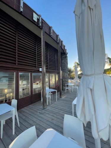 a deck with white chairs and a umbrella at Studio 25 m Manganao Joela 4 personnes avec machine a laver in Saint-François