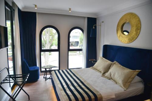 a bedroom with a bed with a blue headboard and two windows at A11 HOTEL Exclusive in Istanbul