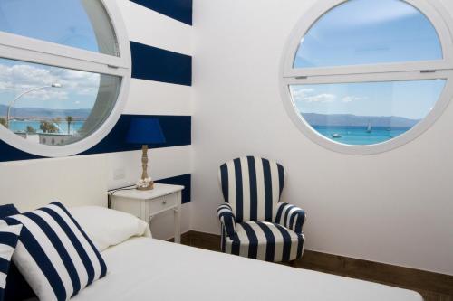 a bedroom with a bed and a chair and two windows at Hotel Nautilus in Cagliari