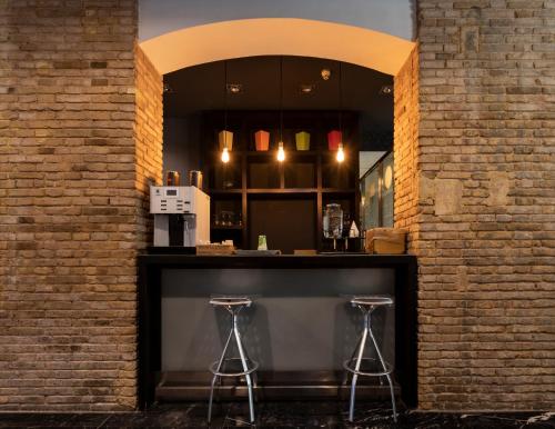 a bar in a brick building with two stools at Petit Palace Ruzafa in Valencia