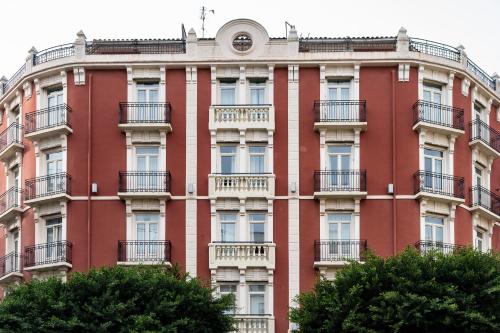 un edificio rojo con balcones y árboles en la parte delantera en Petit Palace Ruzafa, en Valencia