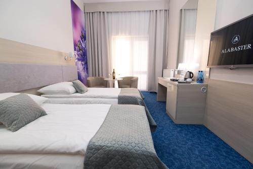 a hotel room with two beds and a television at Alabaster Rezydencja in Rzeszów