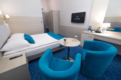 a hotel room with blue chairs and a bed at Alabaster Rezydencja in Rzeszów
