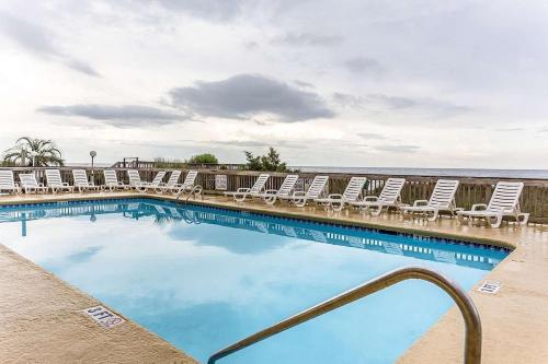 a swimming pool with lounge chairs and the ocean at Ocean Star Hotel in Myrtle Beach