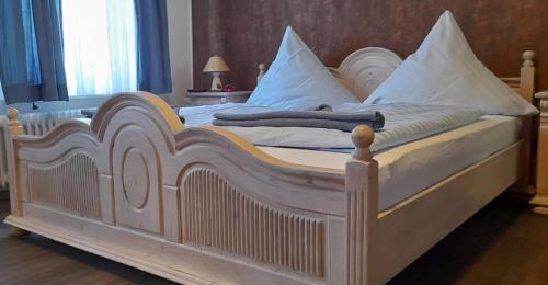 a large bed with white sheets and pillows at Landgasthof Hotel Zur Waage in Marienhafe